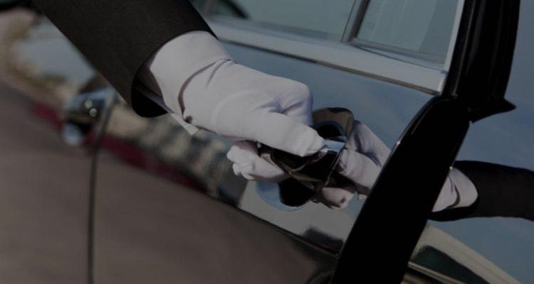 Χέρι με λευκό γάντι ανοίγει την πόρτα ενός αυτοκινήτου.